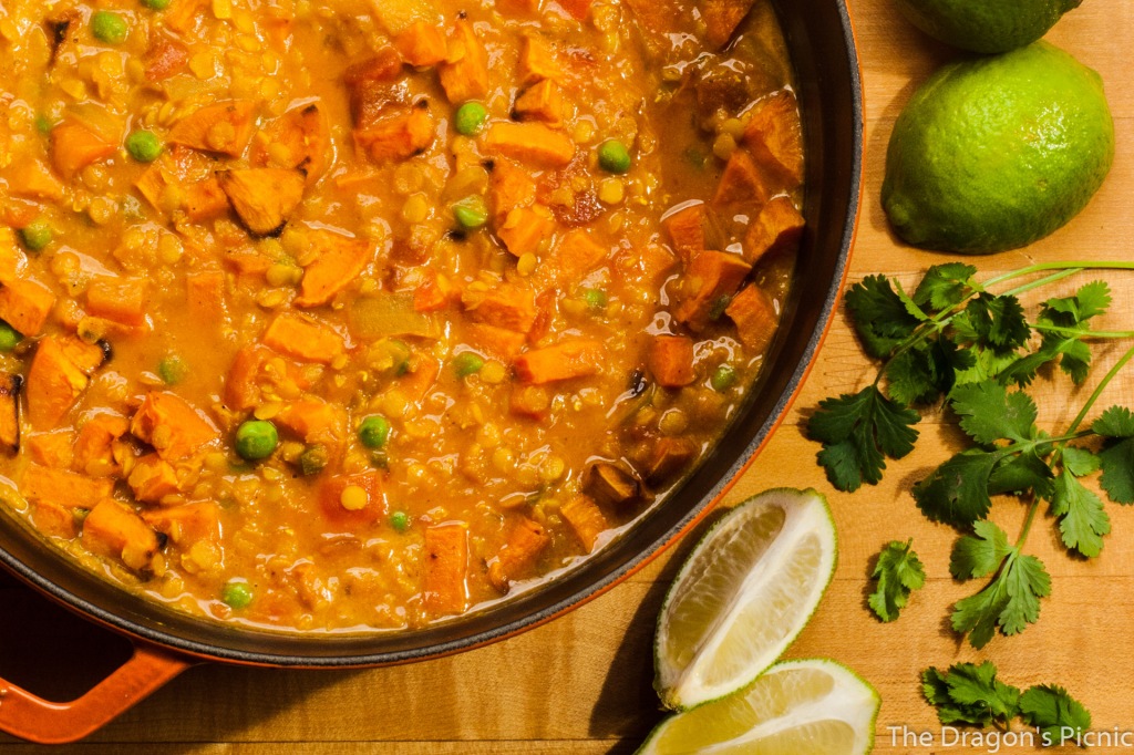 arial view of pot of red lentil and sweet potato stew with limes and cilantro on the side